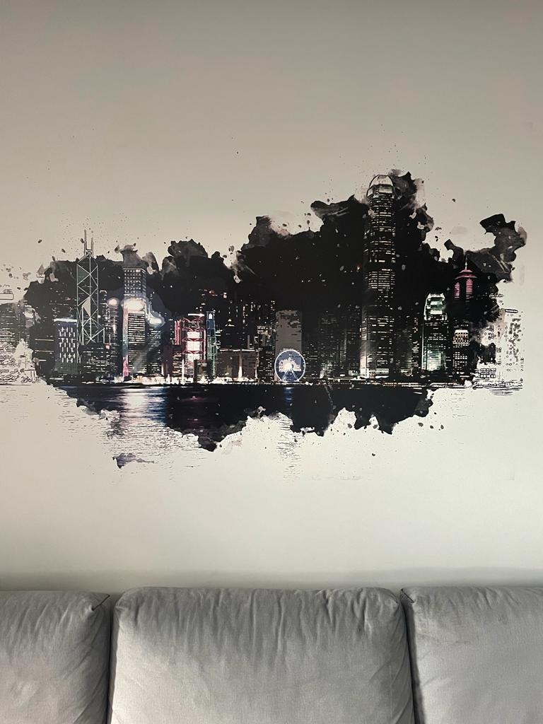 Abstrakcyjny obraz panoramy miasta na ścianie nad szarą sofą w Inowrocławiu, imitujący akwarelę z ciemnymi plamami i refleksami świetlnymi.