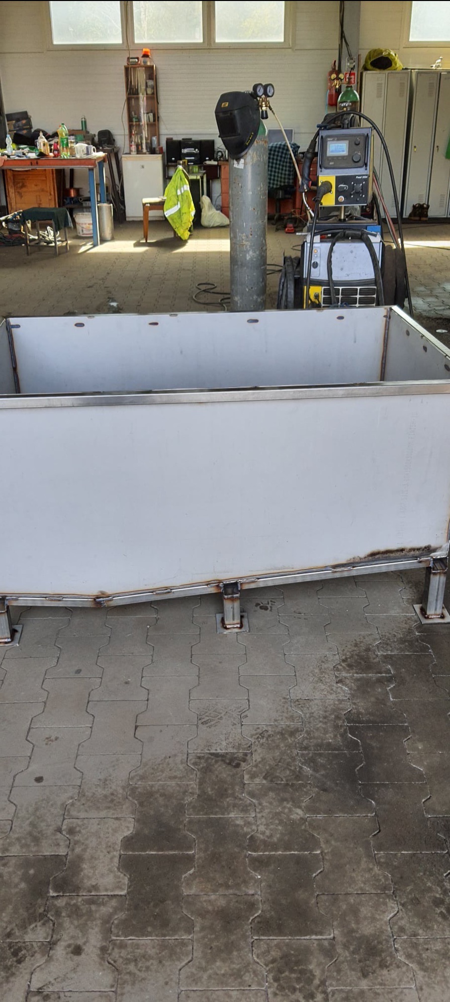 Metalowa konstrukcja w warsztacie, spawana z profili i blach, widoczne spawy i sprzęt spawalniczy w tle.