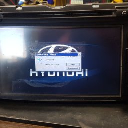 JanSerwis.pl - Samochodowe radio Hyundai z widocznym komunikatem o połączeniu USB na ekranie, leżące na warsztatowym stole.
