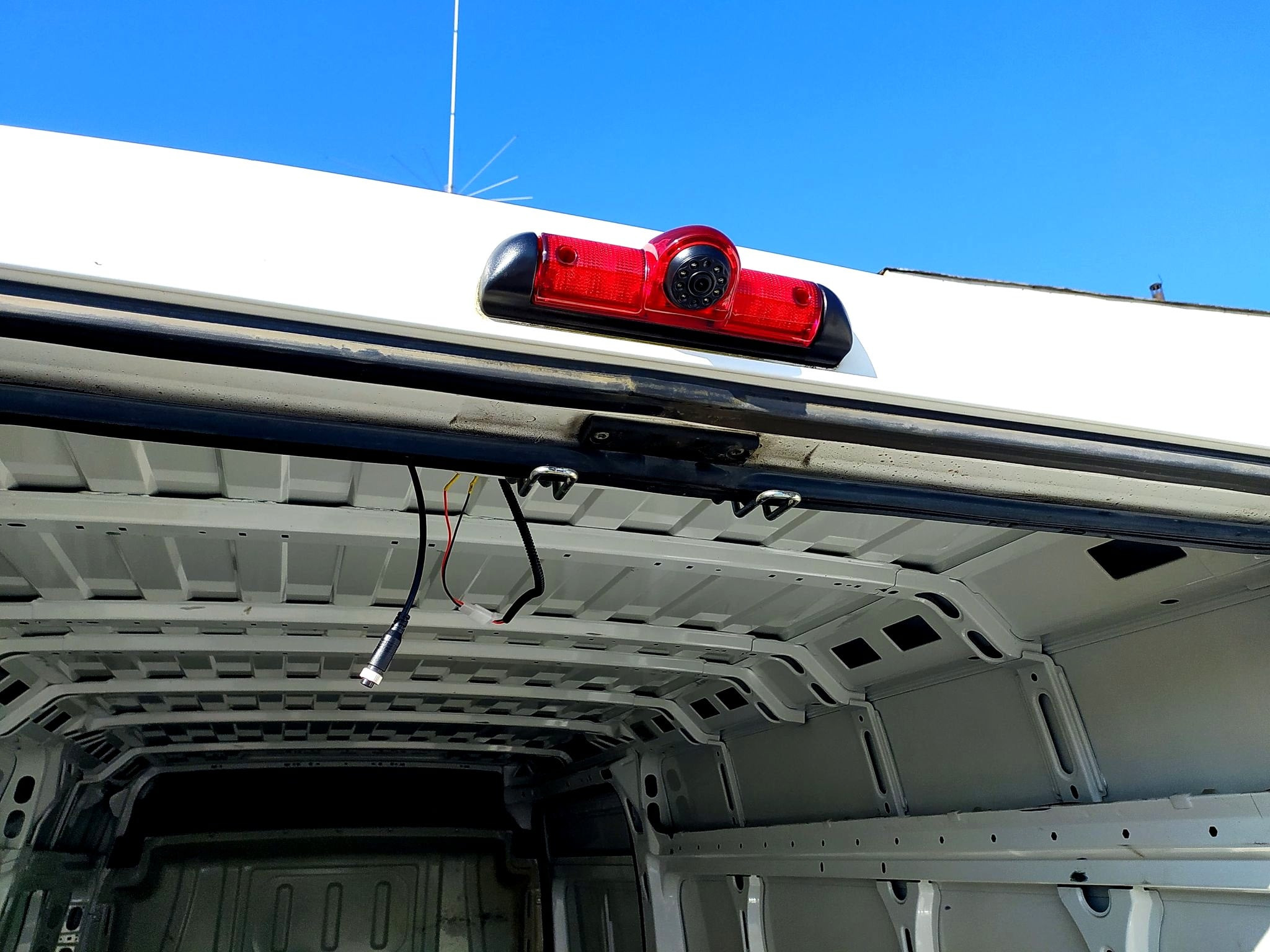 Montaż kamery cofania w samochodzie dostawczym, widoczne przewody i elementy konstrukcyjne pojazdu.