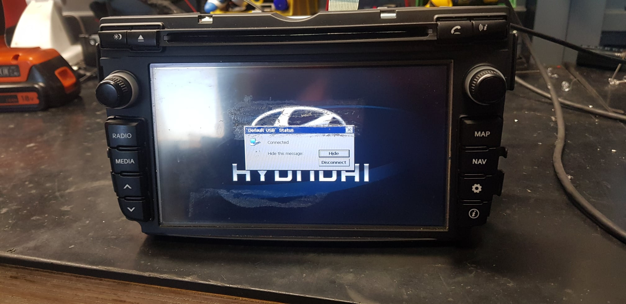 Samochodowe radio Hyundai z widocznym komunikatem o połączeniu USB na ekranie, leżące na warsztatowym stole.