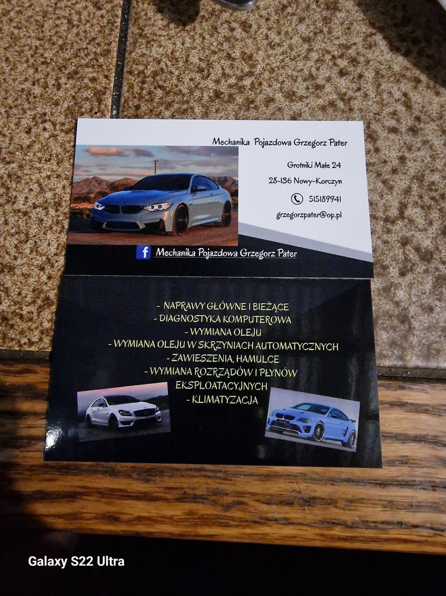Wizytówka warsztatu samochodowego 'Mechanika Pojazdowa Grzegorz Pater' z zdjęciami samochodów, adresem i numerem telefonu, leżąca na brązowym tle.