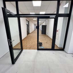 IMA GEFEST SPÓŁKA Z OGRANICZONĄ ODPOWIEDZIALNOŚCIĄ - Wnętrze biura po sprzątaniu: otwarte drzwi, widoczny korytarz z czystą podłogą, wiadro i ściereczka w tle, jasne płytki podłogowe. Perspektywa z dołu.