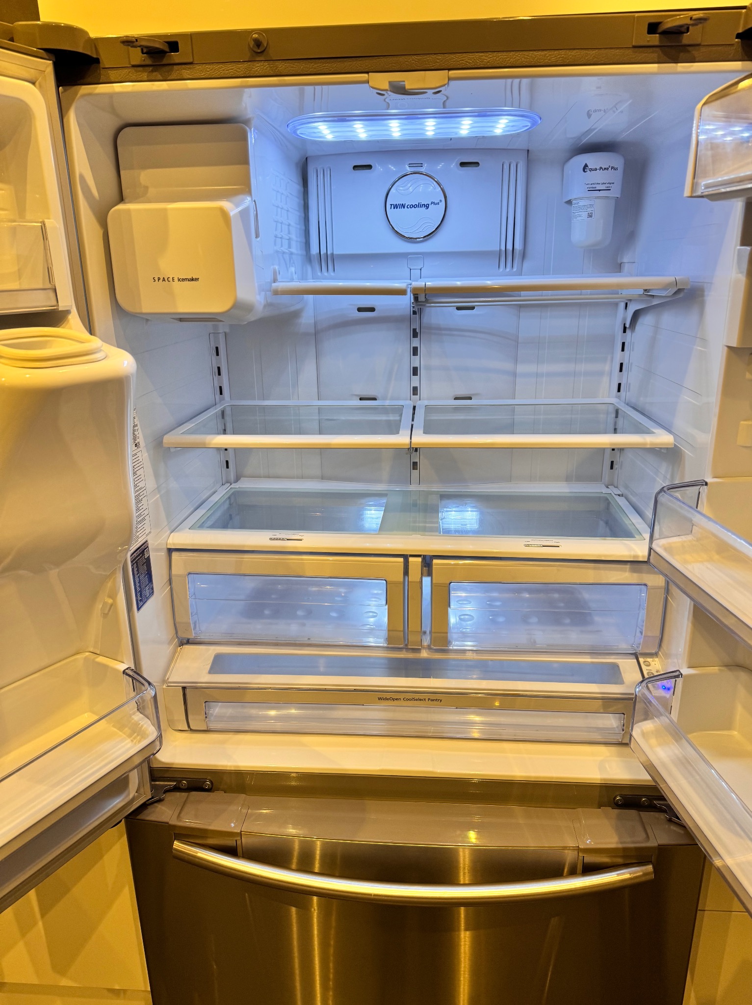 Wnętrze czystej, otwartej lodówki z półkami, szufladami i systemem chłodzenia Twin Cooling Plus.