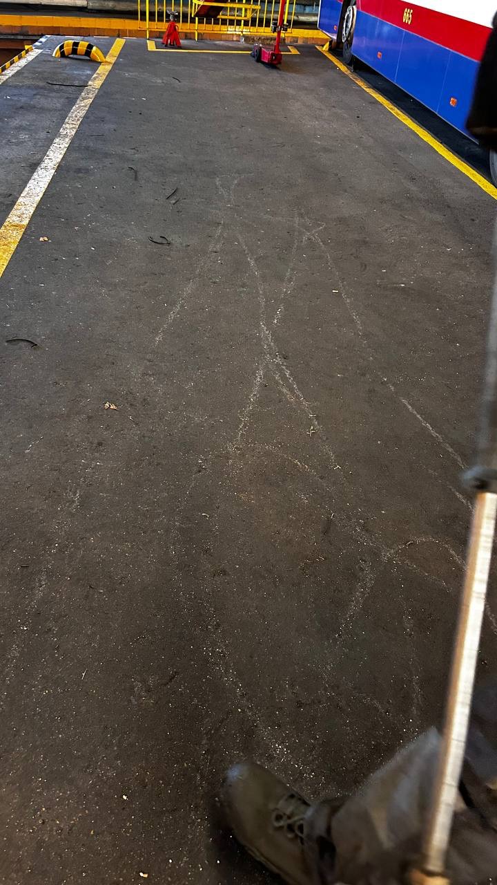 Ślady po czyszczeniu kostki brukowej w Bydgoszczy, widoczne białe zacieki na ciemnej powierzchni. W tle fragment autobusu i elementy wyposażenia.