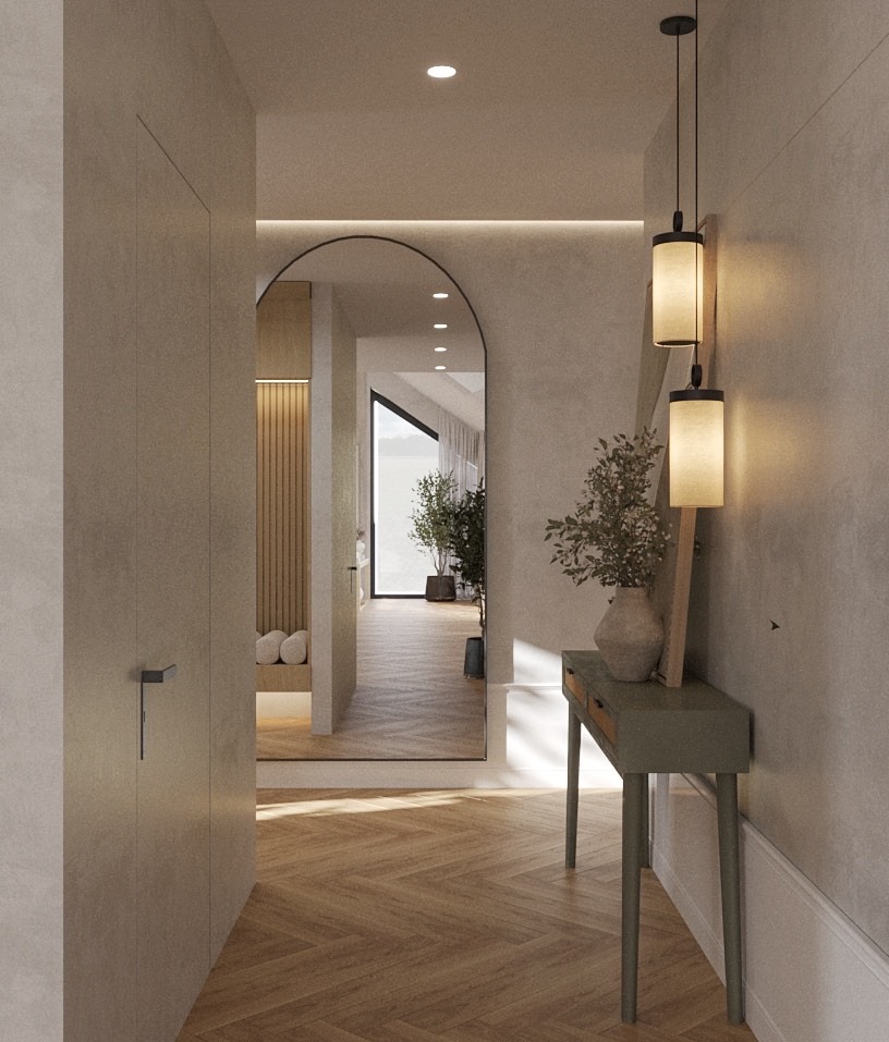Nowoczesny przedpokój z lustrem w łukowej ramie, drewnianą podłogą w jodełkę i minimalistyczną konsolą z lampami. Widok na dalszą część domu.