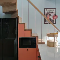 Nowoczesna kuchnia z drewnianymi schodami, zabudowaną mikrofalówką w szafce w odcieniu koralowym, czarną lodówką i plakatem w ramie na ścianie w kolorze baby blue.