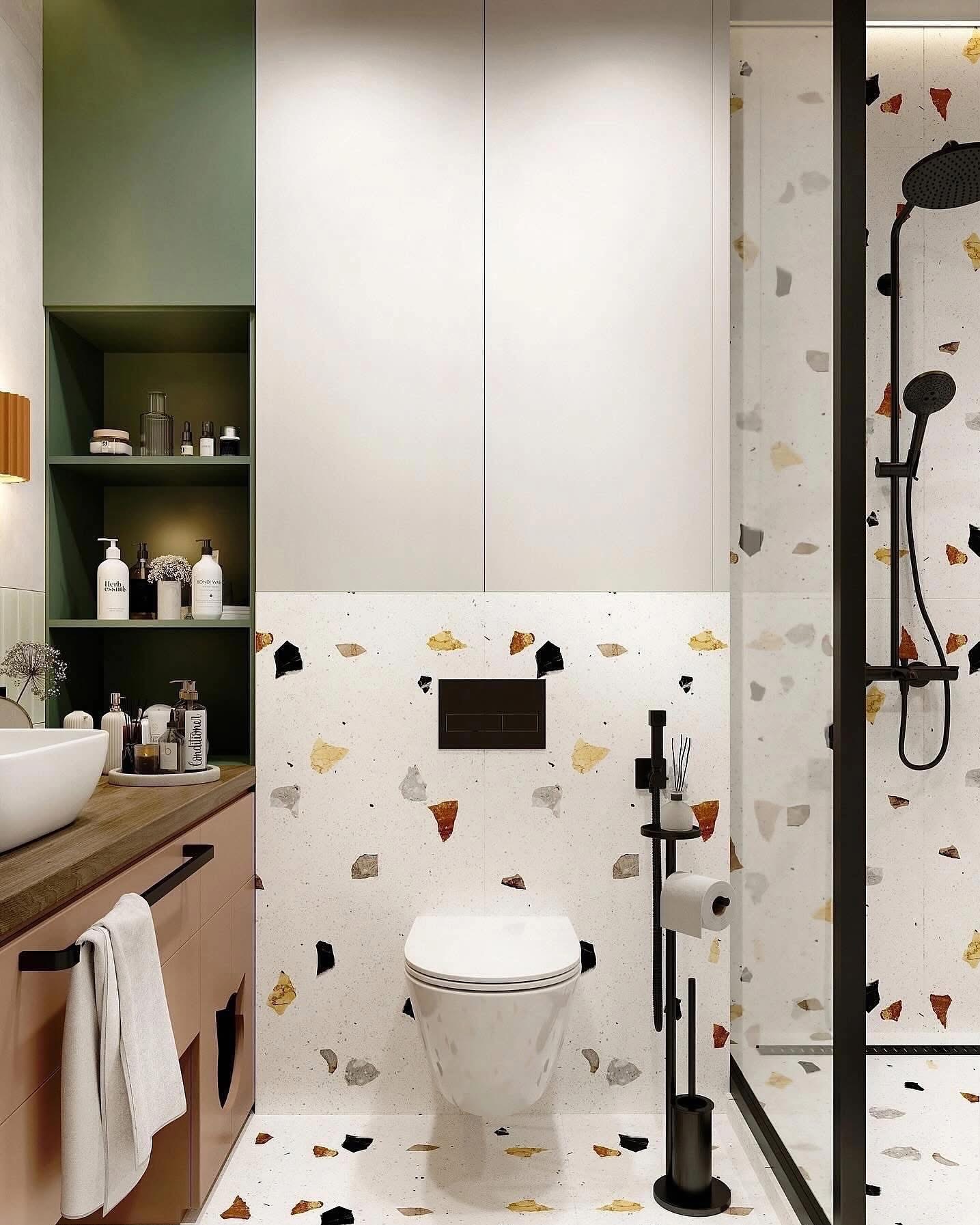 Nowoczesna łazienka z kabiną prysznicową typu walk-in, toaletą podwieszaną i umywalką nablatową, wykończona płytkami lastryko w odcieniach bieli, czerni, złota i terakoty, z czarną armaturą...