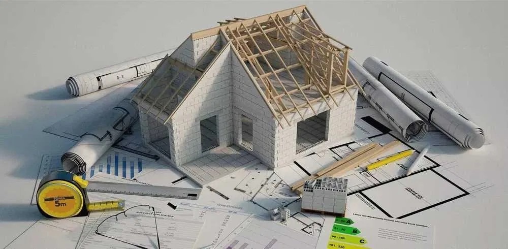 Model domu z bloczków, z widoczną konstrukcją dachu, otoczony planami, miernikiem i świadectwem energetycznym.