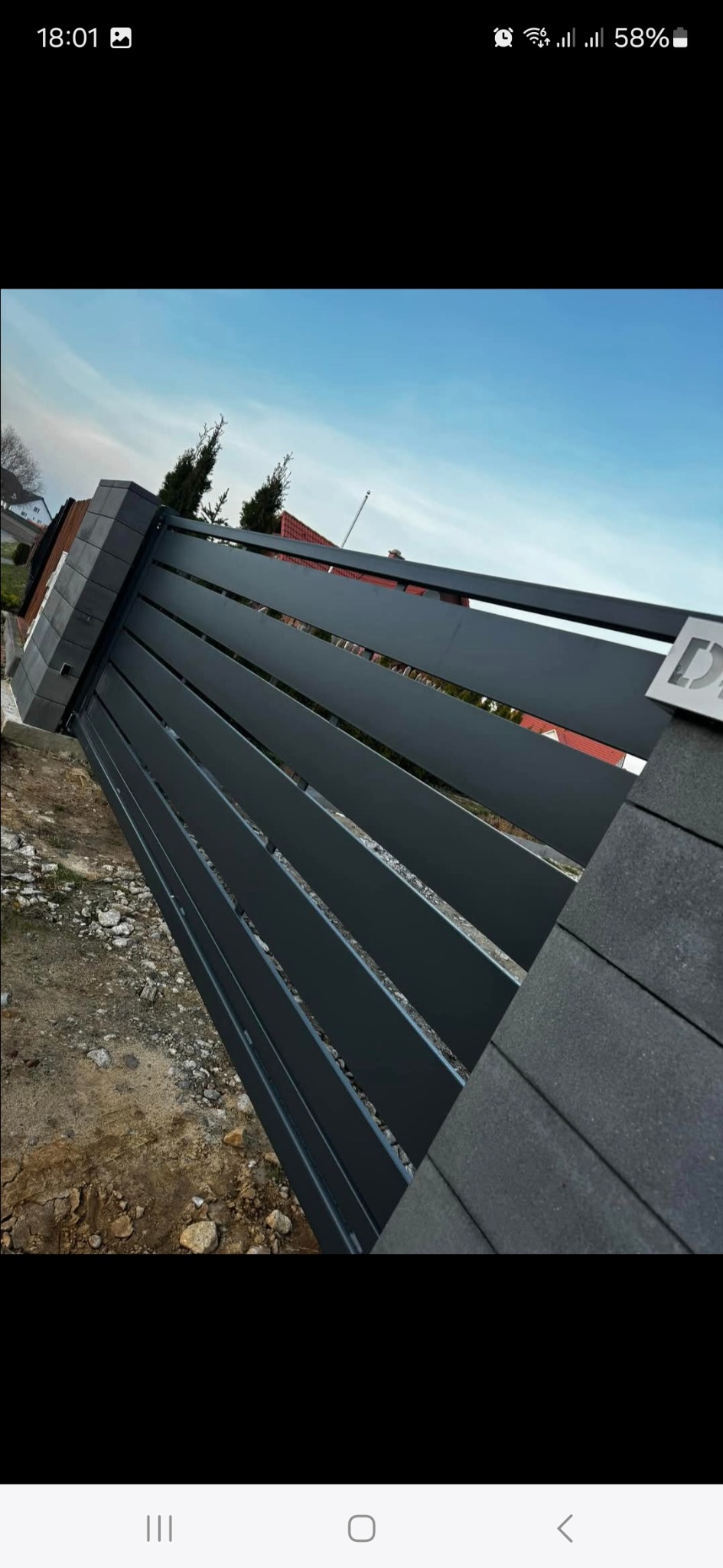 Nowoczesne, poziome przęsła metalowe z elementami betonowymi w Borowie, widok pod kątem, w tle dom i drzewa.