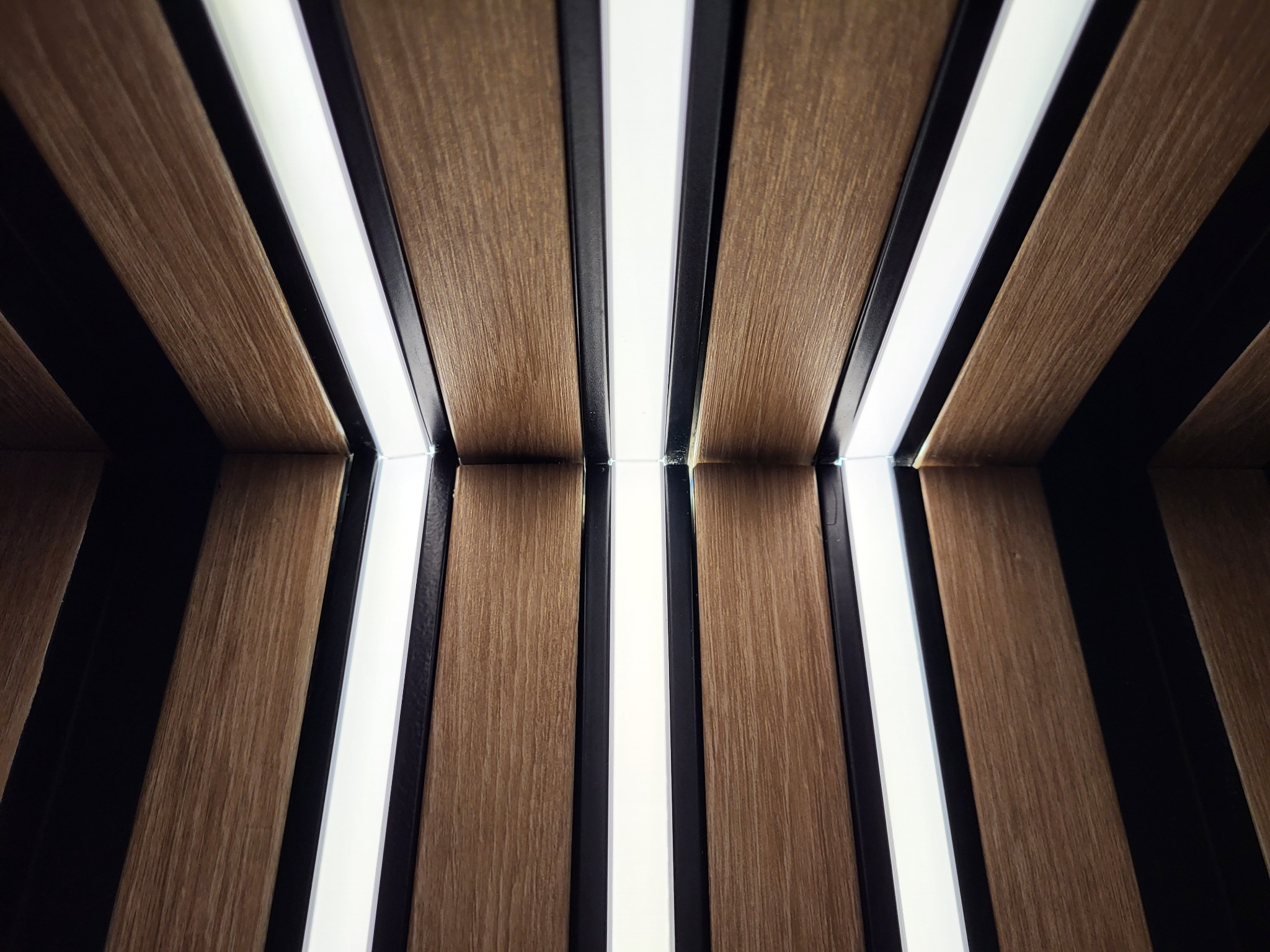 Ukryte oświetlenie LED, montowane pomiędzy drewnianymi lamelkami, tworzące równomierne, nowoczesne podświetlenie.