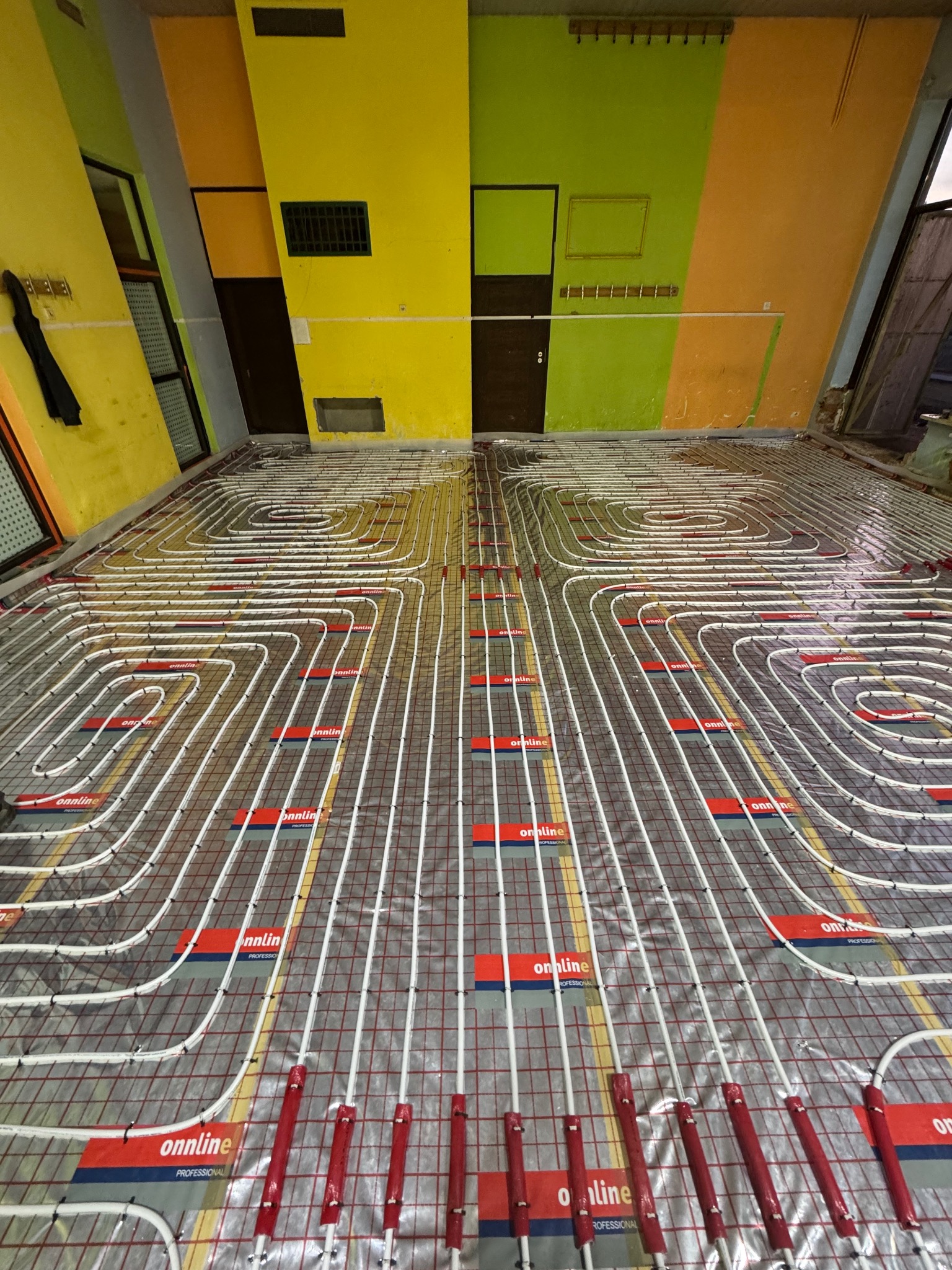 Montaż ogrzewania podłogowego z rur marki Onnline w budynku w Wodzisławiu Śląskim. Widoczne rury ułożone w pętle na siatce montażowej, przed wylaniem posadzki.