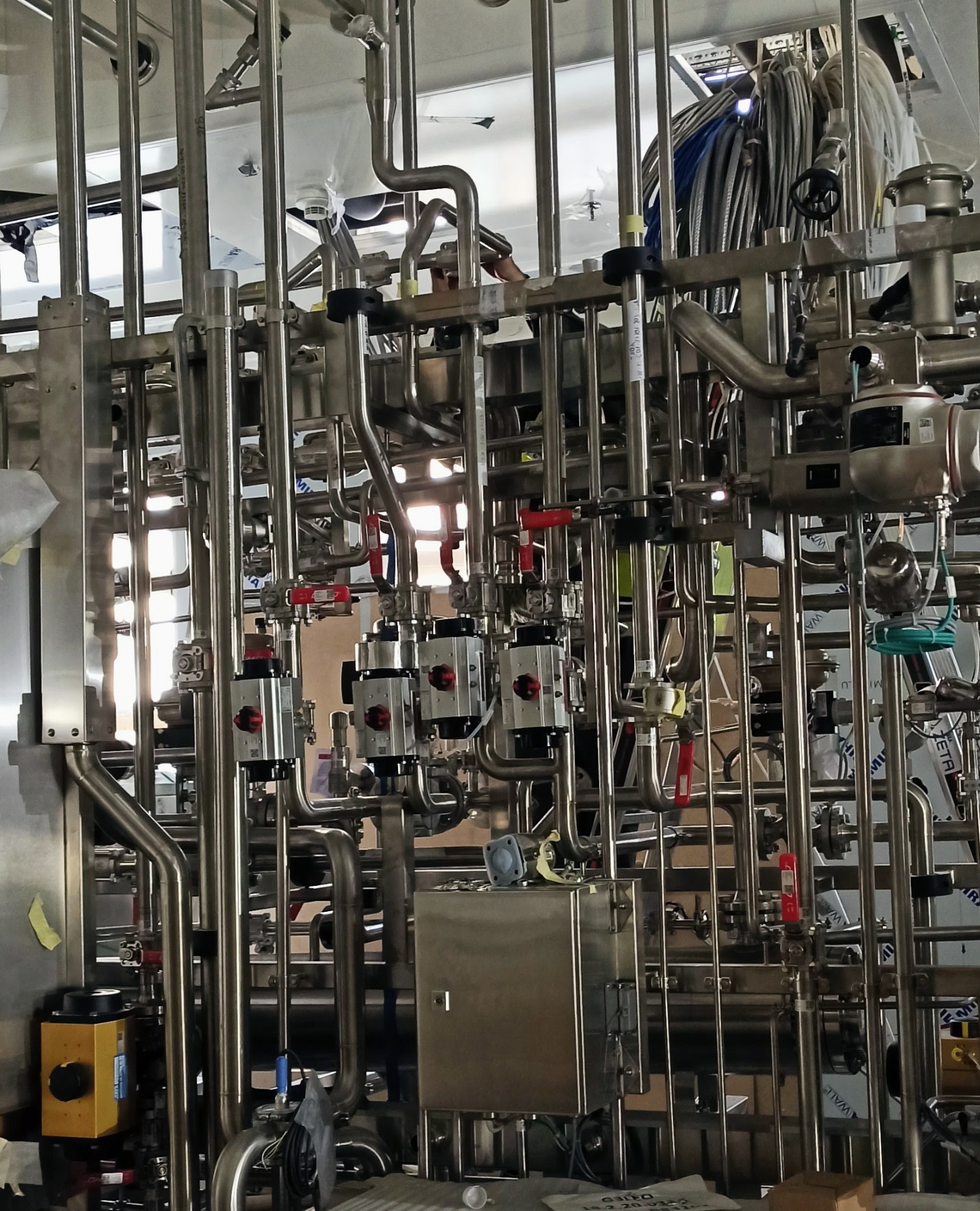 Kompleksowy system rur ze stali nierdzewnej z zaworami i elementami kontrolnymi, tworzący skomplikowaną instalację przemysłową.