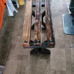 Siespawasiezarabia - Metalowa konstrukcja spawana z trzema drewnianymi siedziskami, częściowo opalonymi, połączonymi nitami.