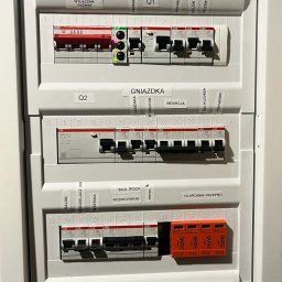 Tomodom Tomasz Turski - Rozdzielnica elektryczna z bezpiecznikami i oznaczeniami obwodów (oświetlenie, gniazdka, siła). Widoczne wyłączniki ABB i zabezpieczenia przepięciowe SIMTEC.