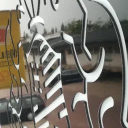 Błyszczący, czarno-biały, wycinany laserowo herb/emblemat z elementami roślinnymi i tarczą, wykonany w Koninie.