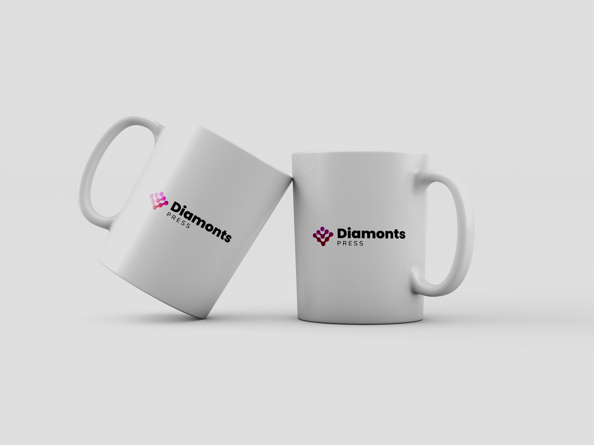 Dwa białe kubki z nadrukowanym logo 'Diamonts PRESS', jeden kubek lekko przechylony, minimalistyczne tło.