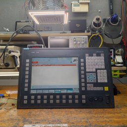 DSN-Elektronika - Panel sterowania CNC Siemens Sinumerik na warsztatowym stole we Wrocławiu, otoczony narzędziami i sprzętem elektronicznym, wyświetlający komunikat 'Czekaj na połączenie z NC/PLC'.