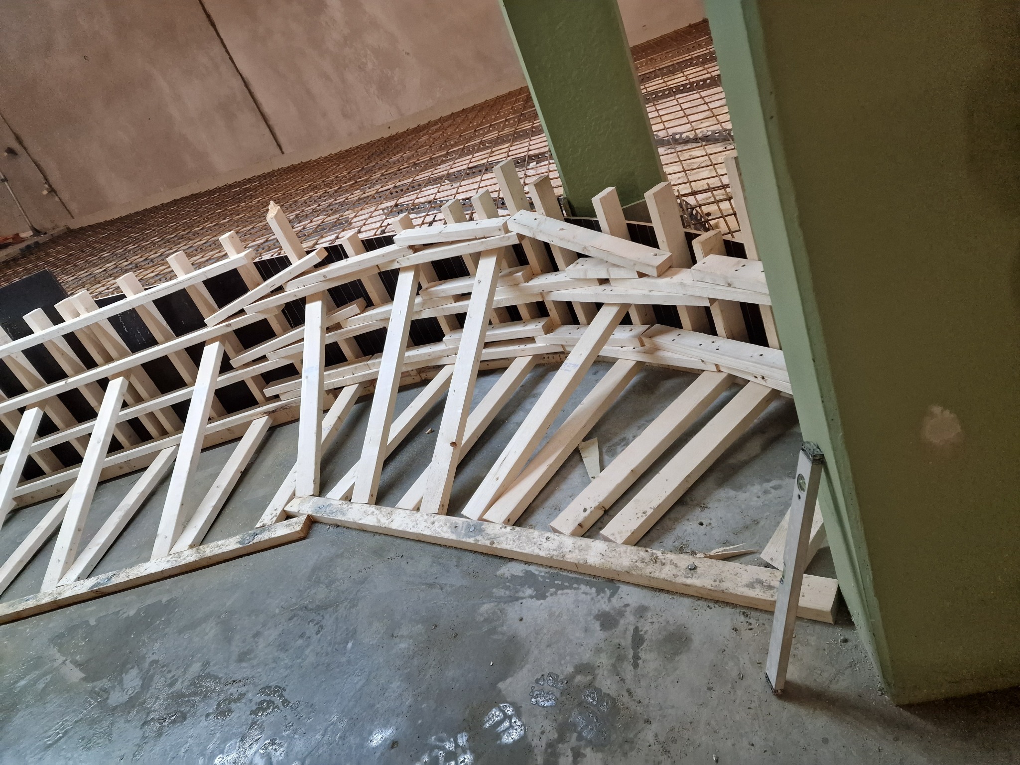 Szczegółowe ujęcie szalunku z desek i zbrojenia stropu w trakcie wylewania betonu. Widoczne narzędzie - poziomica.