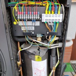 ASKiD sp. z o.o. - Wnętrze pompy ciepła z widocznymi połączeniami elektrycznymi i hydraulicznymi. Precyzyjna instalacja w Bielsko-Białej.