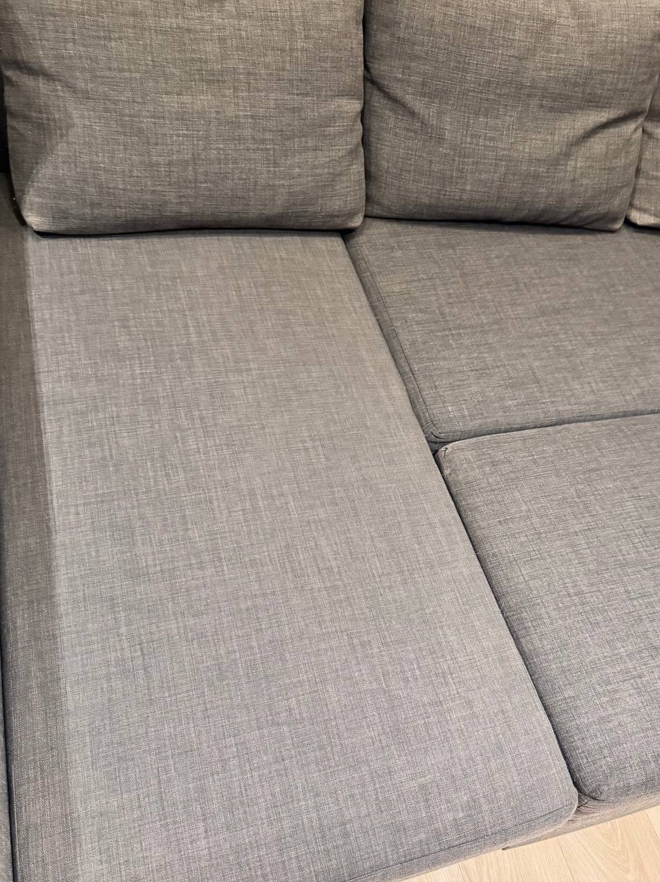 Fragment szarej, tapicerowanej sofy modułowej z widocznymi szwami i fakturą materiału
