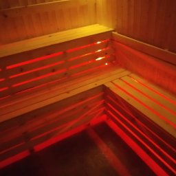 Redwood Tarasy Drewniane - Wnętrze sauny z drewnianymi ławkami, oświetlone czerwonym światłem, widok z góry.