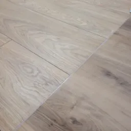 Ułożone panele podłogowe z widocznymi łączeniami i delikatnym wzorem drewna.