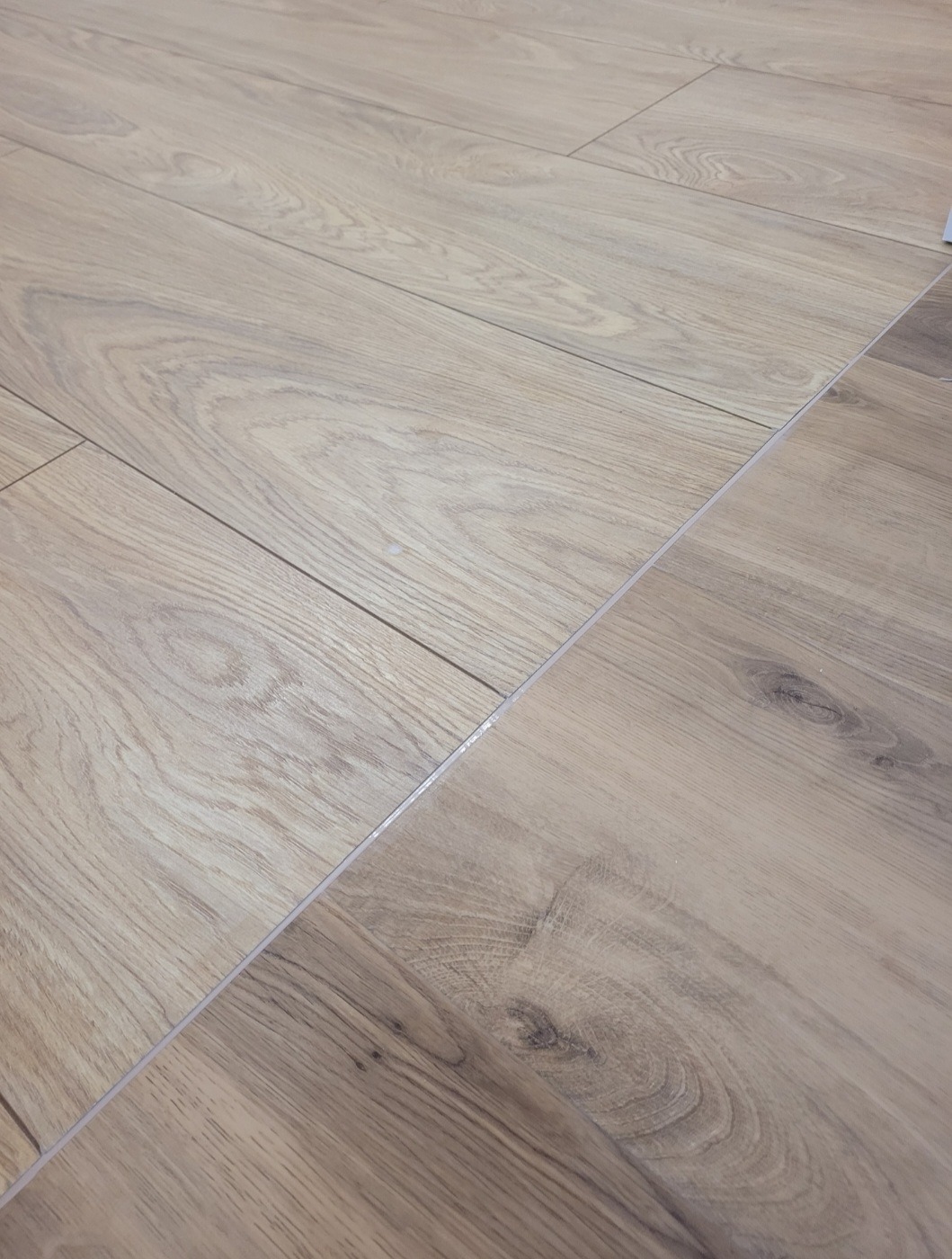 Ułożone panele podłogowe z widocznymi łączeniami i delikatnym wzorem drewna.