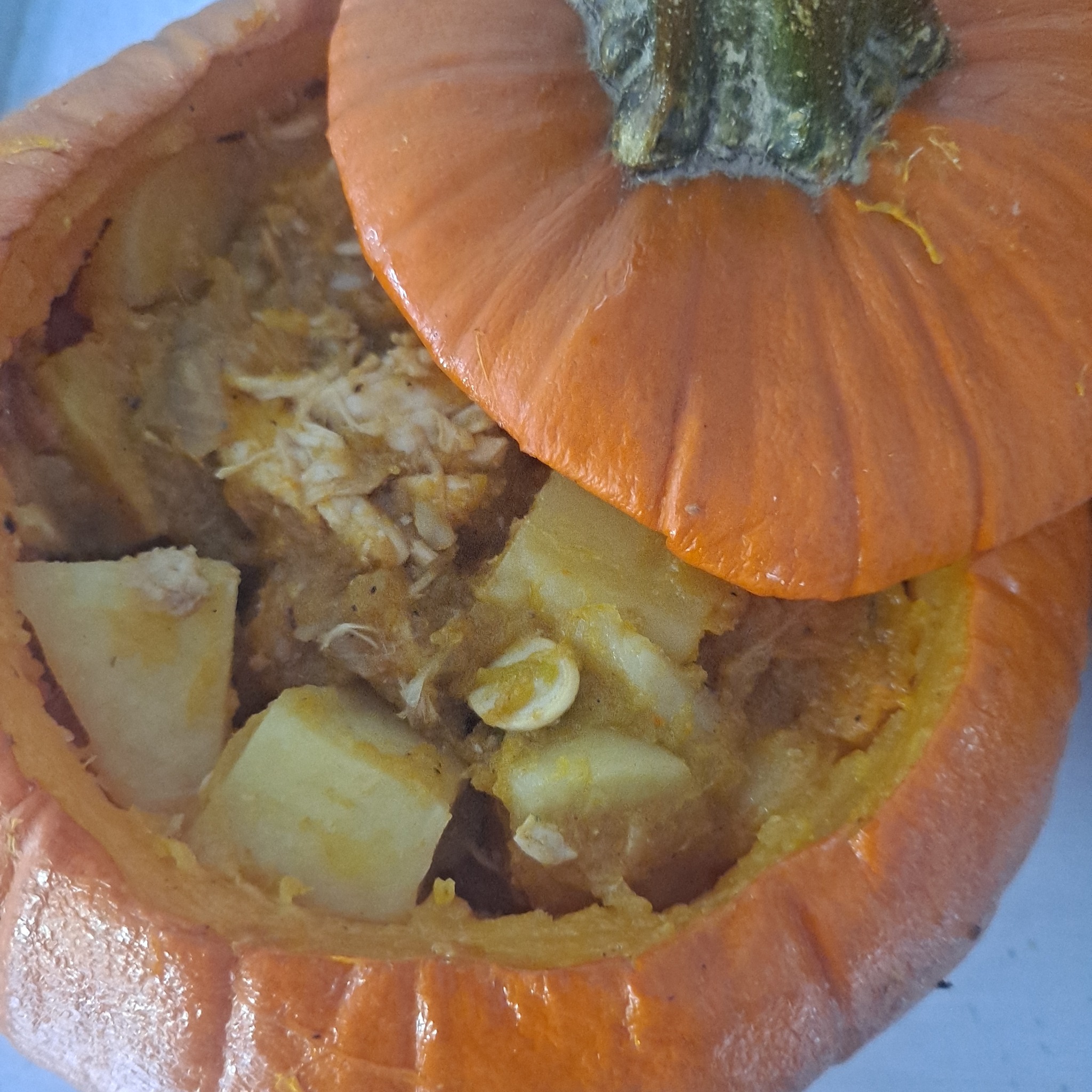 Pieczona dynia wypełniona farszem z ziemniaków i kurczaka, z odciętą górną częścią pełniącą rolę pokrywki.