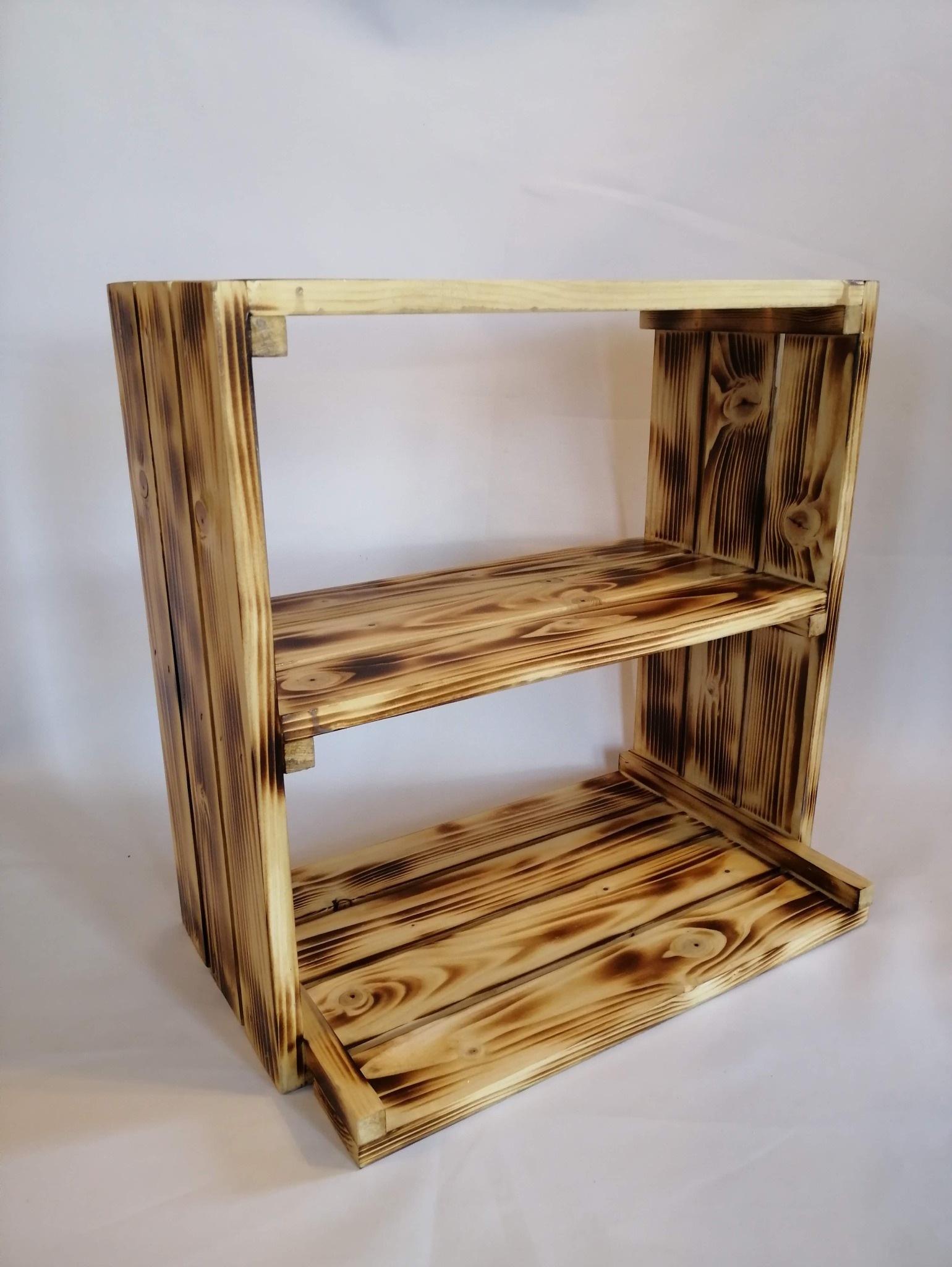 Drewniany regał z dwoma półkami, wykonany z opalanych desek, prezentowany na białym tle.