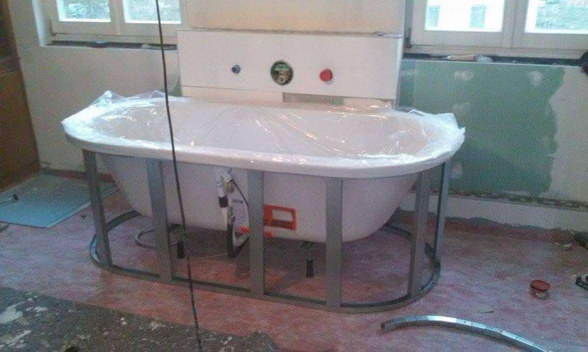 Nowa wanna na metalowym stelażu, zabezpieczona folią, w trakcie prac wykończeniowych łazienki, widoczne niedokończone ściany i podłoga.