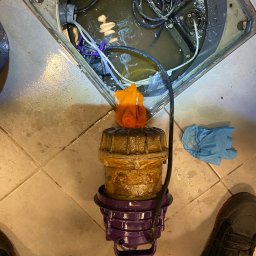 LuLu Instal Bohdan Pasevych - Oczyszczona pompa zanurzeniowa z elementami instalacji w studzience, widoczne przewody i akcesoria. Obok leżą rękawice ochronne i fragment buta.