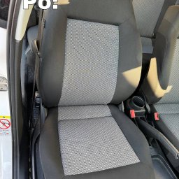 Tamara - Wyraźne zbliżenie na wyczyszczone, szare siedzenie samochodowe z tkaniny w czarnych obramowaniach, widoczne elementy wnętrza pojazdu, po prawej stronie pas bezpieczeństwa, po lewej ostrzeżenie...