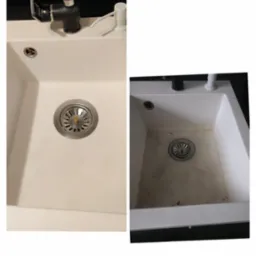 Porównanie: Biały, matowy zlew kuchenny przed i po czyszczeniu, widoczne ślady brudu i osadu, czarny kran z dozownikiem mydła w tle.