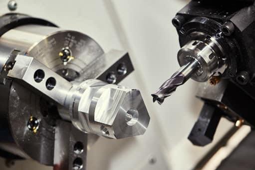 Precyzyjna obróbka metalu na tokarce CNC: frez zbliża się do obracającego się elementu, uchwyconego w solidnym uchwycie tokarskim.