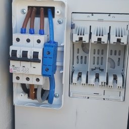 Tech-Net Kamil Machalski - Rozdzielnica elektryczna w trakcie montażu z widocznymi przewodami, bezpiecznikami i narzędziami, ukazująca etap prac instalacyjnych.