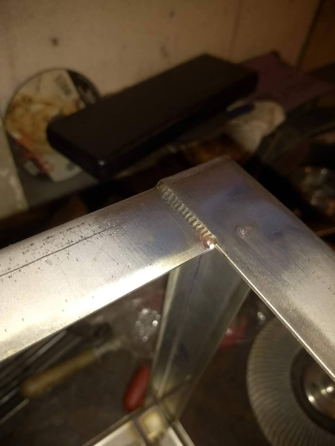 Detal spawu narożnego na ramie z profili aluminiowych, widoczne ślady obróbki i narzędzia w tle.