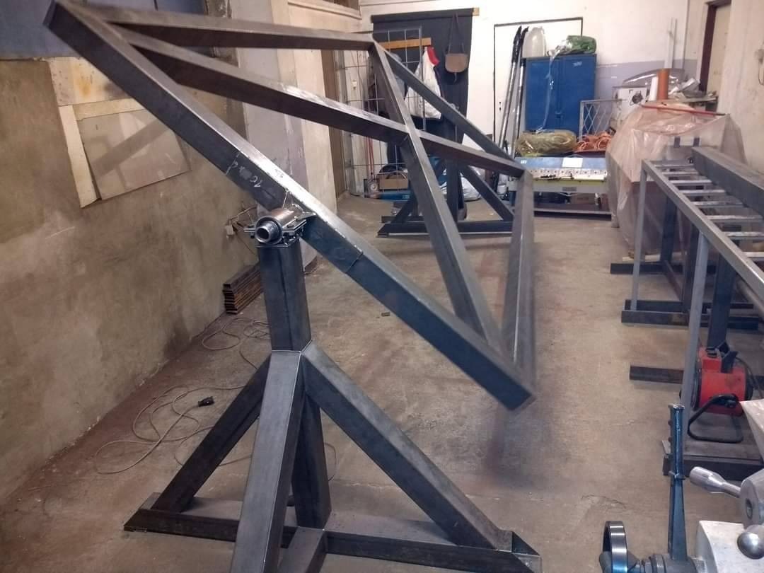 Konstrukcja metalowa na trójnogu, prawdopodobnie element większej konstrukcji stalowej, w warsztacie w Dąbrowie Górniczej. Widoczne ślady spawania.