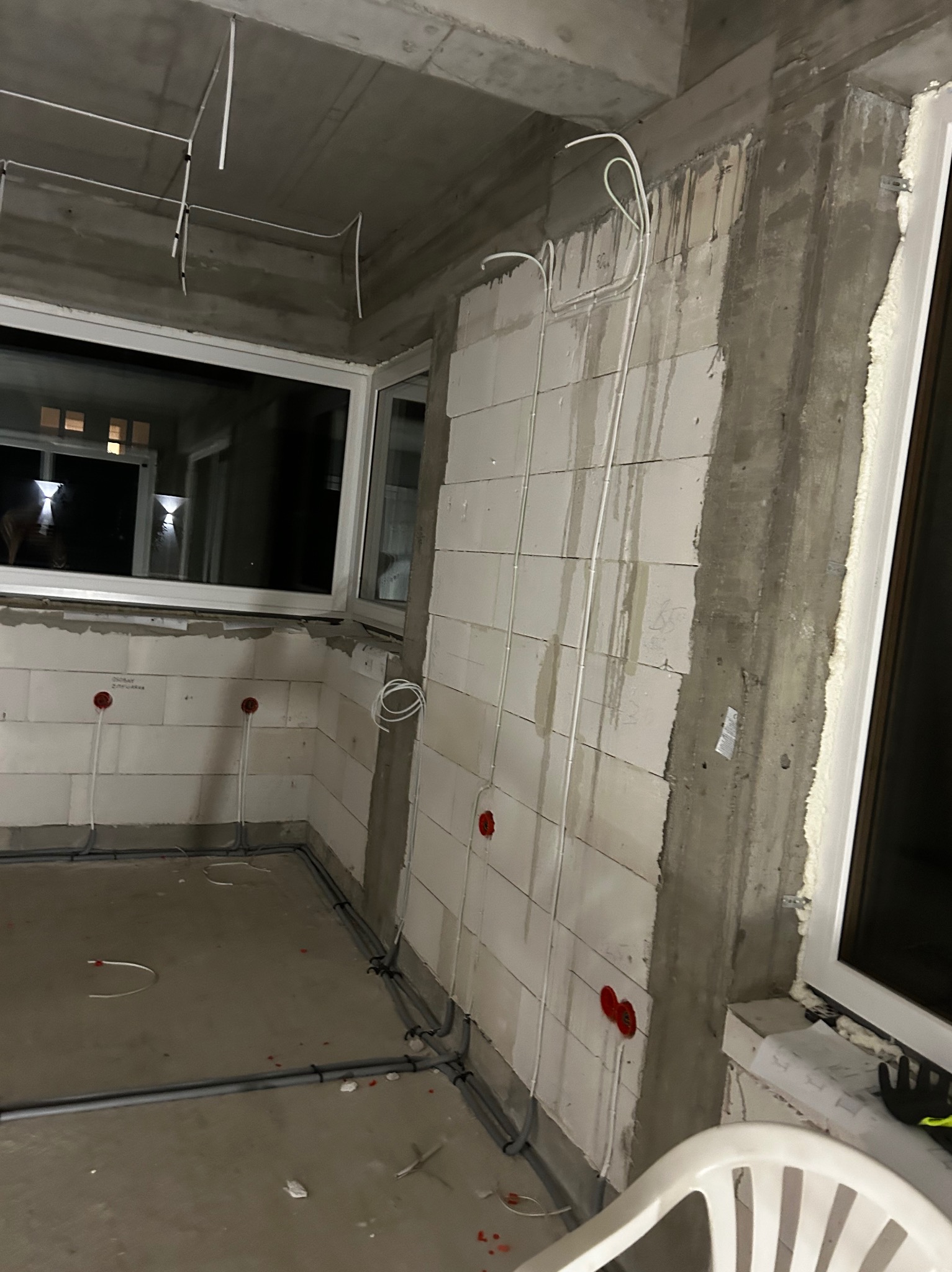 Surowy stan budynku w Łomiankach z widocznymi przewodami elektrycznymi w ścianach i pod sufitem, przygotowanymi do dalszych prac wykończeniowych.