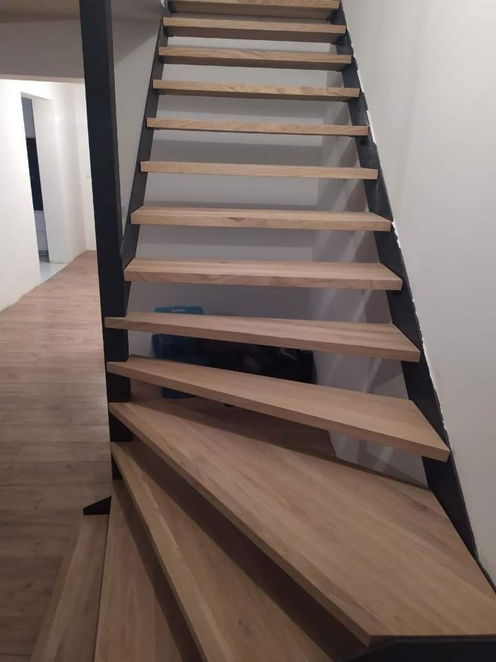 Metalowa konstrukcja schodów z drewnianymi stopniami, widok z dołu, jasne drewno, czarna rama, nowoczesny design.