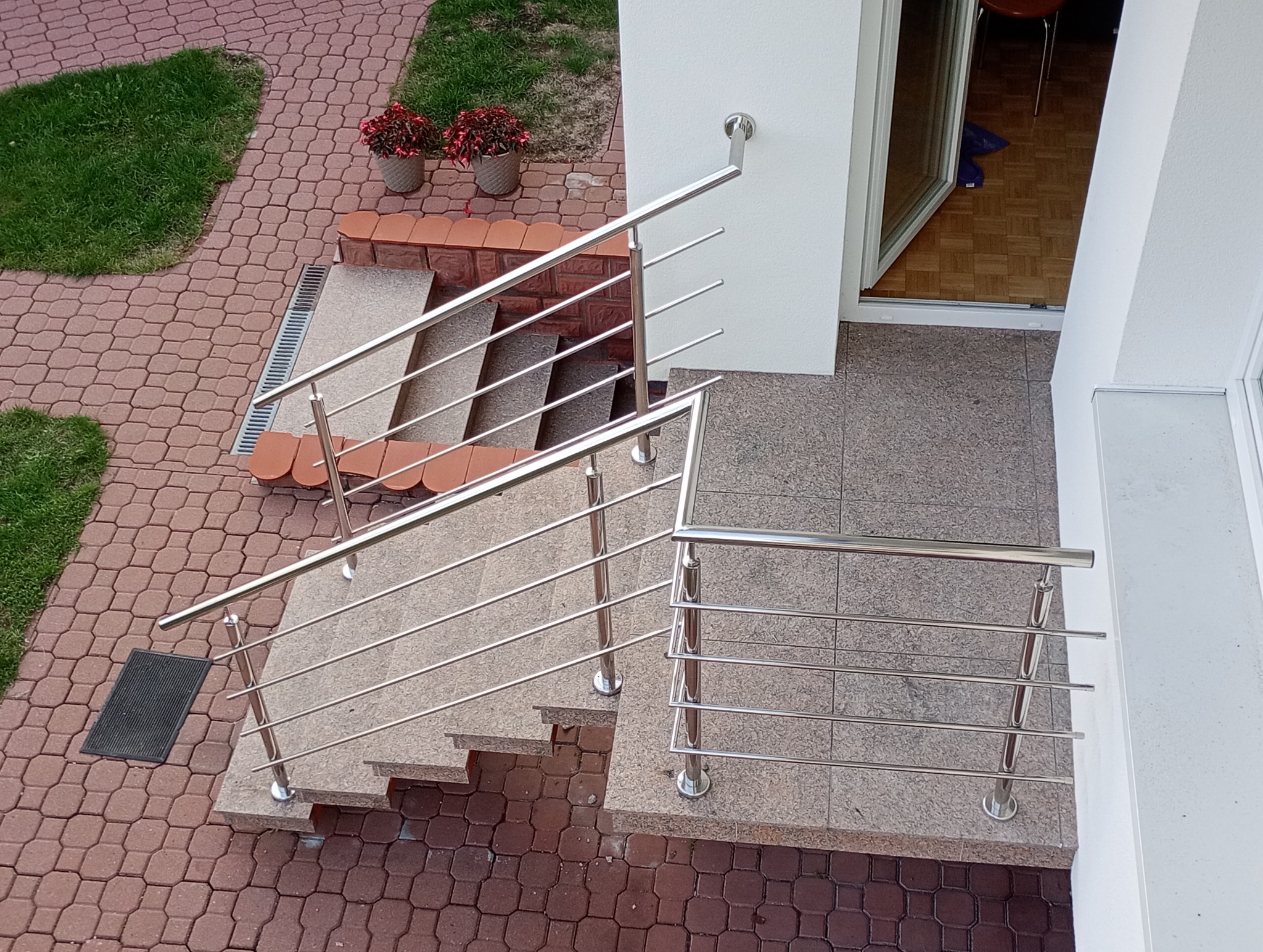 Zewnętrzne schody z granitowymi stopniami i nowoczesną balustradą ze stali nierdzewnej, widok z góry na wejście do domu.