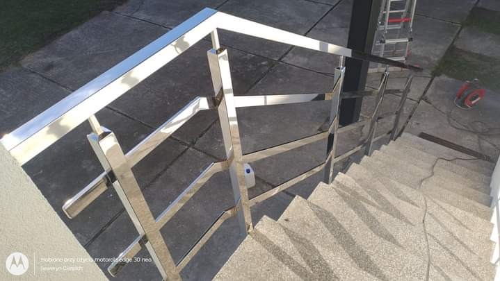 Polerowana, metalowa balustrada schodowa z kwadratowych profili, widok z góry, częściowo zamontowana, widoczna drabina i przedłużacz.