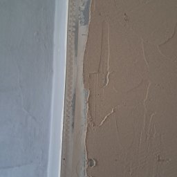 Volodymyr Svirko - Świeżo nałożona warstwa gładzi na ścianie, widoczna listwa narożnikowa z perforacją, surowy stan wykończenia wnętrza.