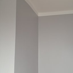 Volodymyr Svirko - Świeżo pomalowany narożnik pokoju w odcieniach szarości, z widoczną białą listwą przysufitową, prezentujący gładką powierzchnię ściany.
