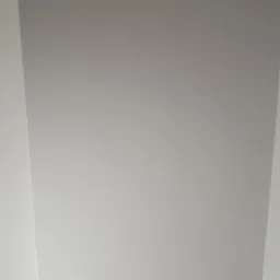 Jasnoszara, gładka powierzchnia sufitu z widocznymi krawędziami ścian, ukazująca wykończenie wnętrza.