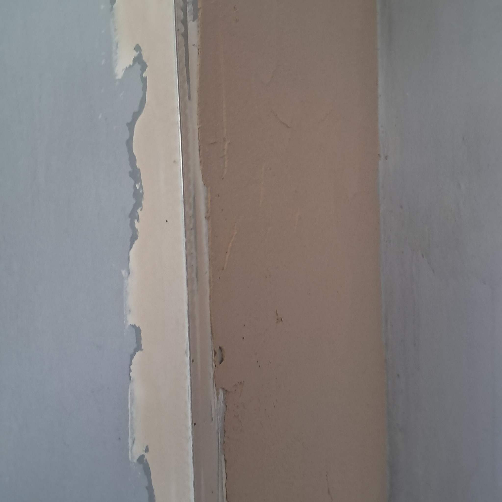 Fragment ściany z widocznymi śladami po usuniętej taśmie malarskiej i nierównościami przed dalszymi pracami wykończeniowymi.