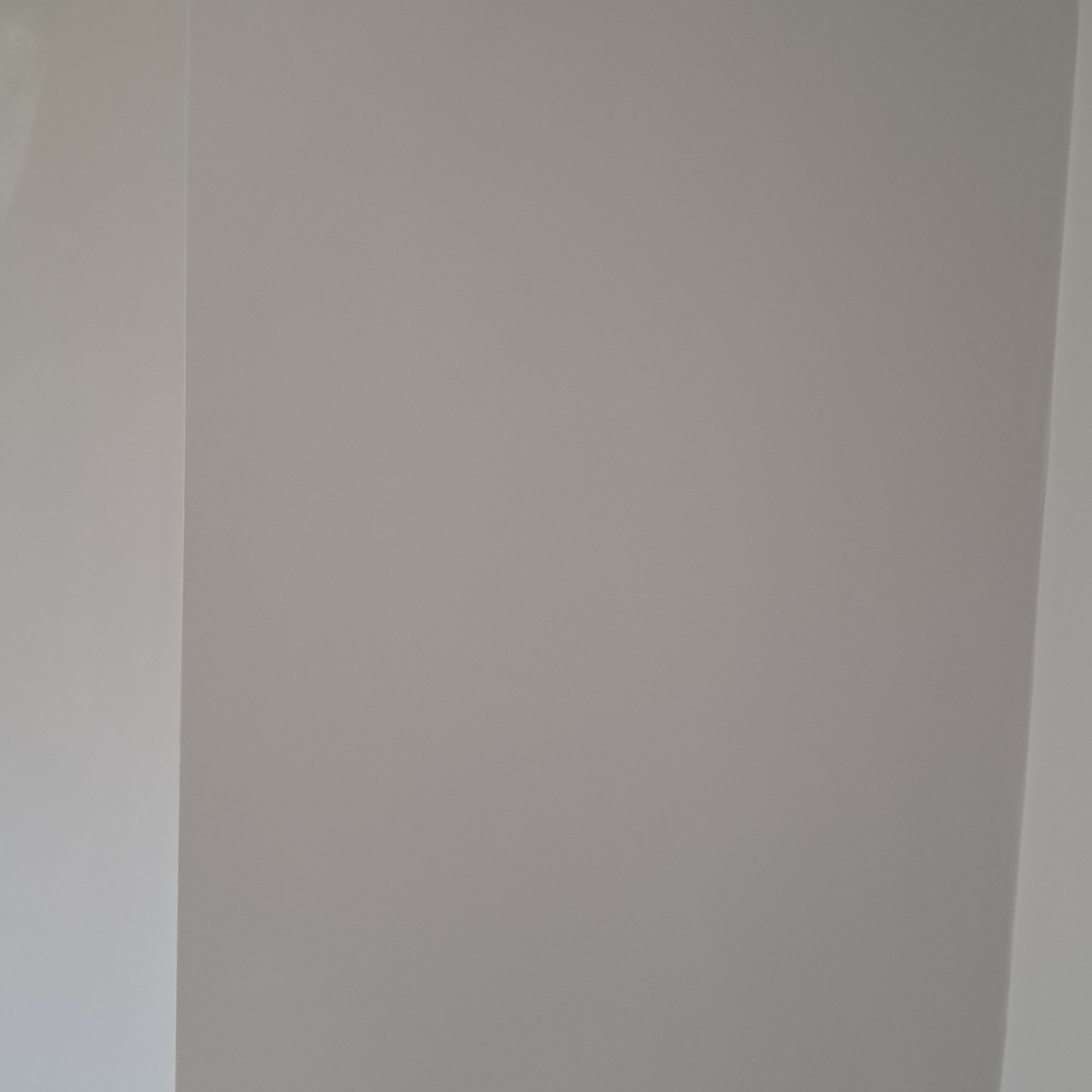 Świeżo pomalowany narożnik pokoju w odcieniach szarości, widoczne delikatne przejścia kolorystyczne i faktura gładzi.