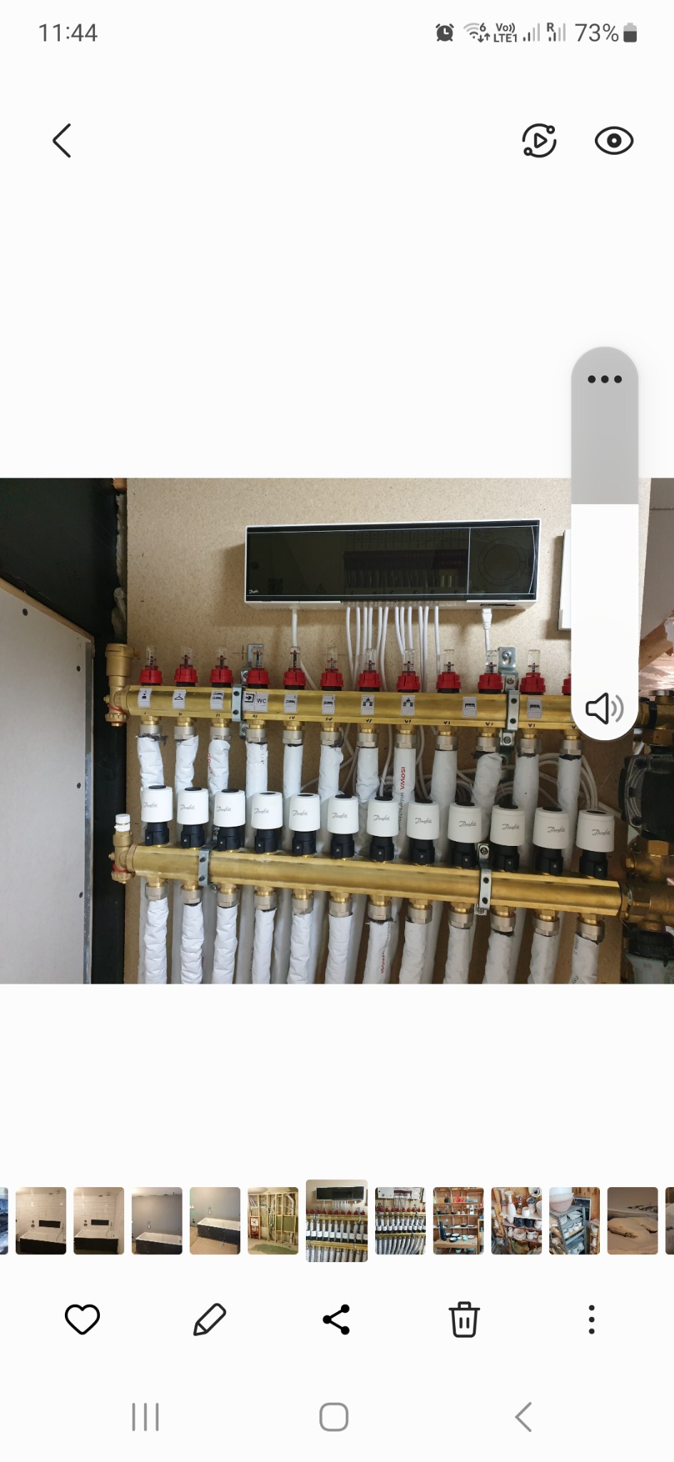 Rozdzielacz ogrzewania podłogowego z rurami, zaworami termostatycznymi Danfoss i automatyką, zamontowany na ścianie z płyty OSB.