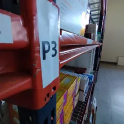 Półka regałowa w magazynie z oznaczeniem 'P3', wypełniona kartonami z lekami i suplementami diety.