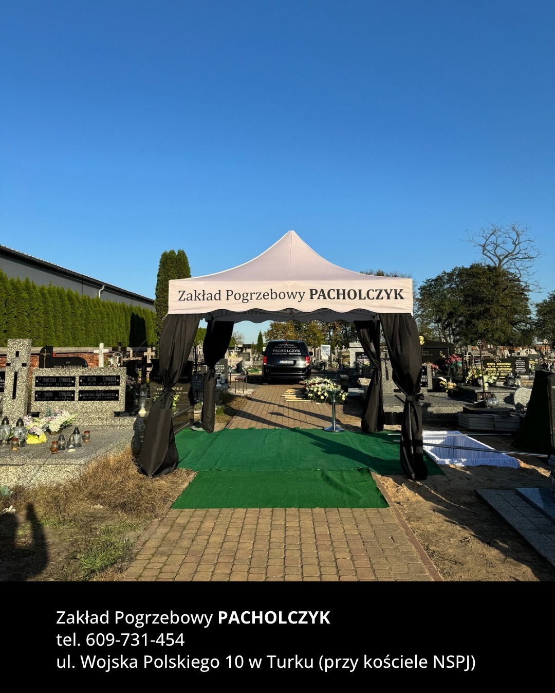 Teren cmentarza z rozstawionym namiotem pogrzebowym Zakładu Pogrzebowego PACHOLCZYK, widoczny karawan i kwiaty.
